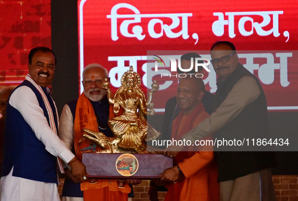 Uttar Pradesh Chief Minister Yogi Adityanath presents a statue of Ganga during the inauguration of various development projects for the '202...