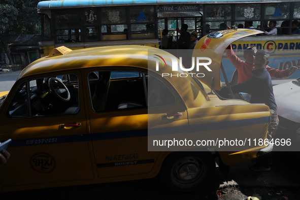 A taxi driver places luggage in the boot space of an iconic yellow ambassador taxi in Kolkata, India, on December 13, 2024. The Calcutta Hig...