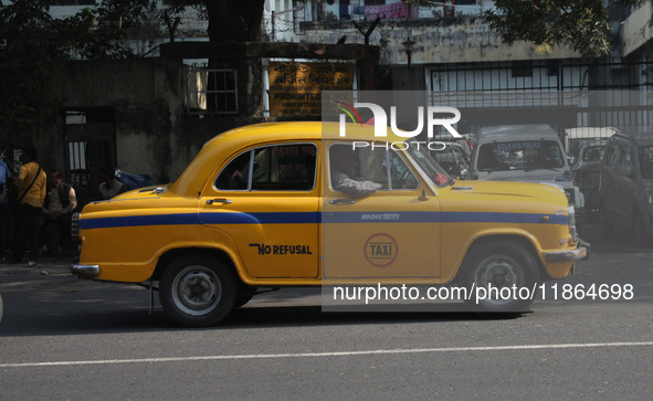 A taxi drives past an office building with its iconic yellow Ambassador taxi in Kolkata, India, on December 13, 2024. The Calcutta High Cour...