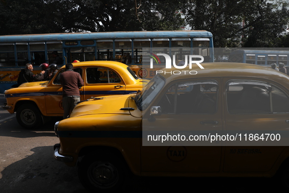 A passenger speaks with a taxi driver before riding in an iconic yellow Ambassador taxi in Kolkata, India, on December 13, 2024. The Calcutt...