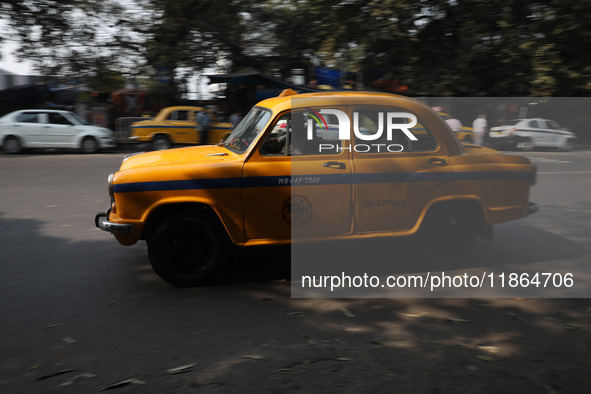 A taxi drives past an office building with its iconic yellow Ambassador taxi in Kolkata, India, on December 13, 2024. The Calcutta High Cour...