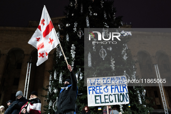 An anti-government protester holds a placard reading ''we demand free and fair elections'' during a demonstration against the Georgian gover...