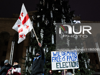 An anti-government protester holds a placard reading ''we demand free and fair elections'' during a demonstration against the Georgian gover...