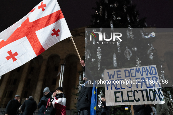 An anti-government protester holds a placard reading ''we demand free and fair elections'' during a demonstration against the Georgian gover...