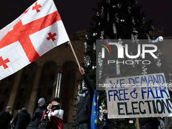 An anti-government protester holds a placard reading ''we demand free and fair elections'' during a demonstration against the Georgian gover...