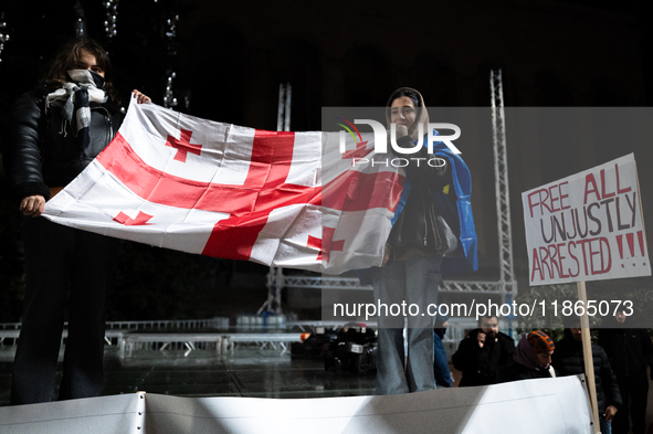 An anti-government protester holds a placard reading ''free all unjustly arrested !!!'' during a demonstration against the Georgian governme...