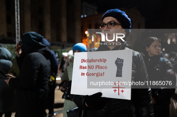 An anti-government protester holds a placard reading ''dictatorship has no place in Georgia'' during a demonstration against the Georgian go...