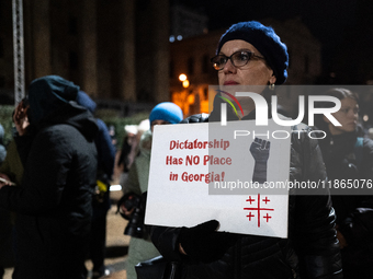 An anti-government protester holds a placard reading ''dictatorship has no place in Georgia'' during a demonstration against the Georgian go...