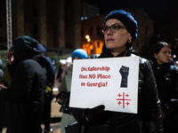 An anti-government protester holds a placard reading ''dictatorship has no place in Georgia'' during a demonstration against the Georgian go...