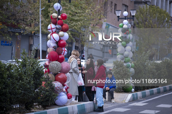 Iranian women stand together next to Christmas decorations put up by the municipality of District Six while Christmas shopping in downtown T...