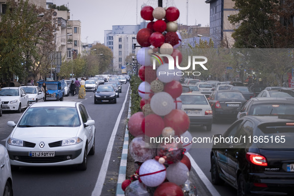 Vehicles drive past Christmas decorations put up by the municipality of District Six while people shop for Christmas in downtown Tehran, Ira...