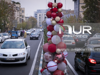 Vehicles drive past Christmas decorations put up by the municipality of District Six while people shop for Christmas in downtown Tehran, Ira...