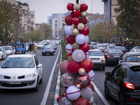 Vehicles drive past Christmas decorations put up by the municipality of District Six while people shop for Christmas in downtown Tehran, Ira...