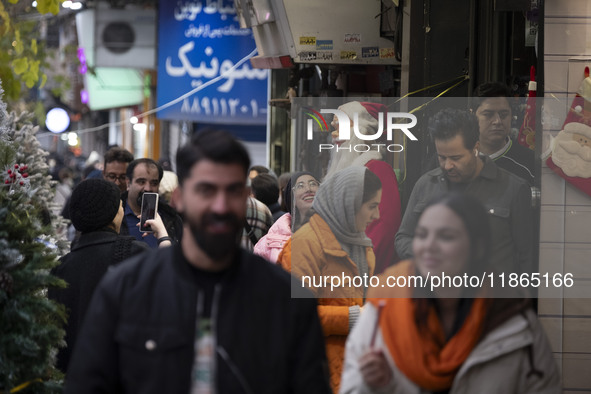 A young Iranian woman smiles as she looks at a statue of Santa Claus while Christmas shopping in downtown Tehran, Iran, on December 13, 2024...