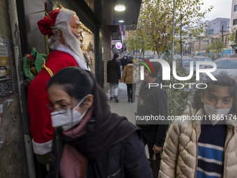 Young Iranian women walk past a statue of Santa Claus while Christmas shopping in downtown Tehran, Iran, on December 13, 2024. Iranian-Chris...