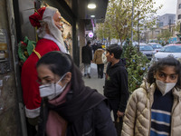 Young Iranian women walk past a statue of Santa Claus while Christmas shopping in downtown Tehran, Iran, on December 13, 2024. Iranian-Chris...