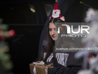 A young Iranian-Christian woman wears Christmas accessories and holds a gift box while shopping for Christmas in downtown Tehran, Iran, on D...