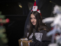 A young Iranian-Christian woman wears Christmas accessories and holds a gift box while shopping for Christmas in downtown Tehran, Iran, on D...