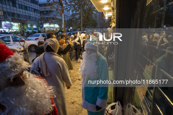 An Iranian-Christian man dressed as Santa Claus stands on a sidewalk during Christmas shopping in downtown Tehran, Iran, on December 13, 202...