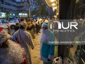 An Iranian-Christian man dressed as Santa Claus stands on a sidewalk during Christmas shopping in downtown Tehran, Iran, on December 13, 202...