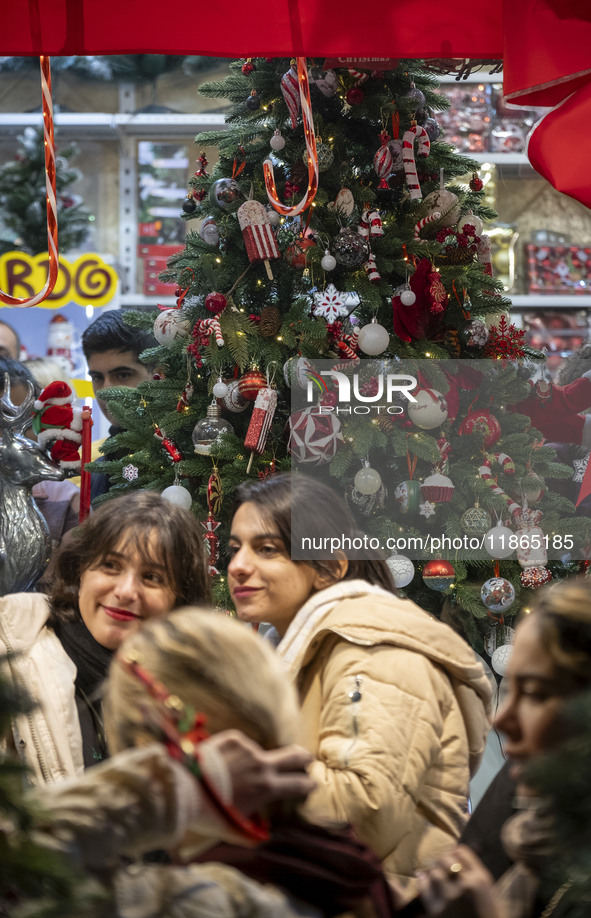 Two young Iranian women stand together in front of a Christmas tree during Christmas shopping in downtown Tehran, Iran, on December 13, 2024...