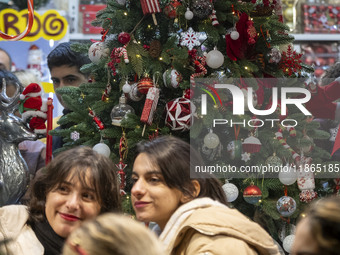 Two young Iranian women stand together in front of a Christmas tree during Christmas shopping in downtown Tehran, Iran, on December 13, 2024...