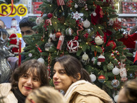 Two young Iranian women stand together in front of a Christmas tree during Christmas shopping in downtown Tehran, Iran, on December 13, 2024...