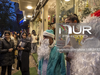 A young Iranian woman holds her birthday cake while standing next to two Iranian-Christian men dressed as Santa Claus during Christmas shopp...