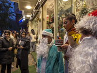 A young Iranian woman holds her birthday cake while standing next to two Iranian-Christian men dressed as Santa Claus during Christmas shopp...