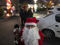 An Iranian-Christian man dressed as Santa Claus sits on a street-side during Christmas shopping in downtown Tehran, Iran, on December 13, 20...