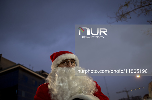 An Iranian-Christian man dressed as Santa Claus stands on a street during Christmas shopping in downtown Tehran, Iran, on December 13, 2024,...