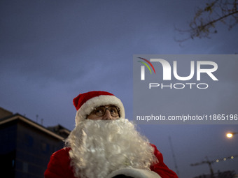 An Iranian-Christian man dressed as Santa Claus stands on a street during Christmas shopping in downtown Tehran, Iran, on December 13, 2024,...