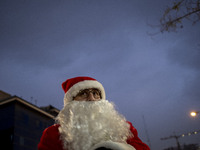 An Iranian-Christian man dressed as Santa Claus stands on a street during Christmas shopping in downtown Tehran, Iran, on December 13, 2024,...