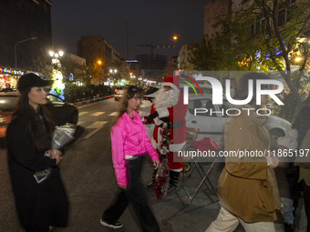 Young Iranian women walk past an Iranian-Christian man dressed as Santa Claus standing on a street-side during Christmas shopping in downtow...