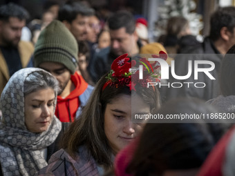 A young Iranian woman wears a Christmas accessory as she walks along a sidewalk while Christmas shopping in downtown Tehran, Iran, on Decemb...