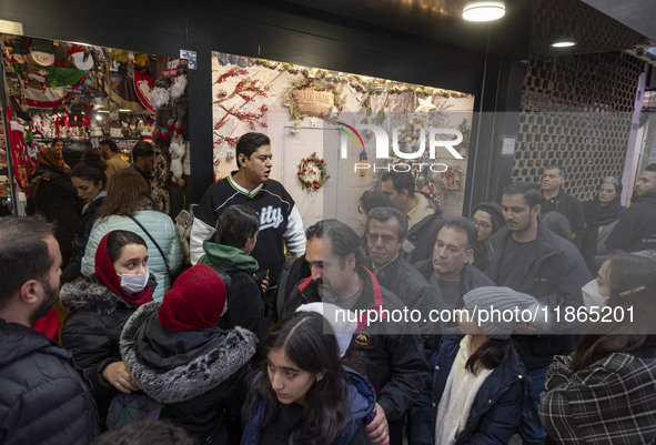 Iranian-Christian people stand in line while waiting to enter a shop decorated for Christmas shopping in downtown Tehran, Iran, on December...