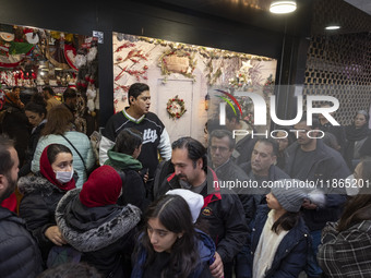 Iranian-Christian people stand in line while waiting to enter a shop decorated for Christmas shopping in downtown Tehran, Iran, on December...