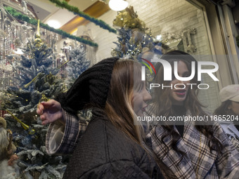 Young Iranian women stand in front of a shop window decorated for Christmas shopping in downtown Tehran, Iran, on December 13, 2024. Iranian...