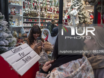 Young Iranian women take a selfie as they pose next to Christmas accessories outside a shop during Christmas shopping in downtown Tehran, Ir...