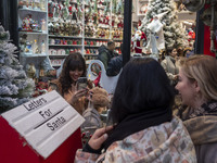 Young Iranian women take a selfie as they pose next to Christmas accessories outside a shop during Christmas shopping in downtown Tehran, Ir...