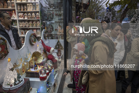 An Iranian woman and her young daughter look at a shop window decorated for Christmas shopping in downtown Tehran, Iran, on December 13, 202...