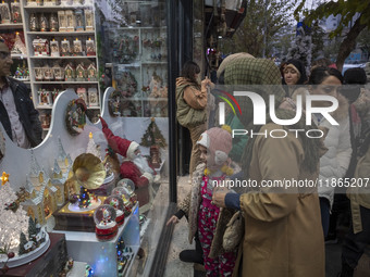 An Iranian woman and her young daughter look at a shop window decorated for Christmas shopping in downtown Tehran, Iran, on December 13, 202...