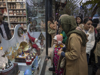 An Iranian woman and her young daughter look at a shop window decorated for Christmas shopping in downtown Tehran, Iran, on December 13, 202...