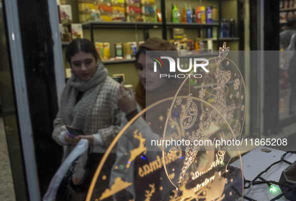 Two young Iranian women walk past Christmas accessories during Christmas shopping in downtown Tehran, Iran, on December 13, 2024. While Iran...