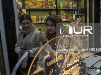 Two young Iranian women walk past Christmas accessories during Christmas shopping in downtown Tehran, Iran, on December 13, 2024. While Iran...