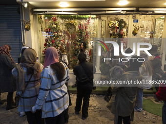 Young Iranian women stand on a sidewalk outside a shop decorated for Christmas shopping in downtown Tehran, Iran, on December 13, 2024. Whil...