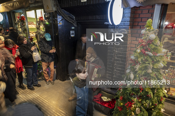 An Iranian street musician plays the accordion on a sidewalk during Christmas shopping in downtown Tehran, Iran, on December 13, 2024. Irani...