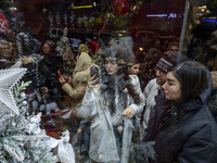 A young Iranian woman wearing a hat takes photographs of a shop window decorated for Christmas shopping in downtown Tehran, Iran, on Decembe...