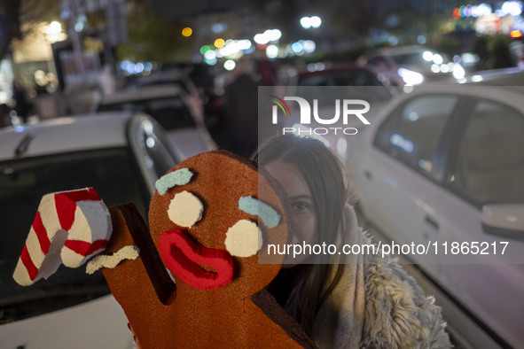 A young Iranian woman poses for a photograph while holding a Christmas accessory during Christmas shopping in downtown Tehran, Iran, on Dece...