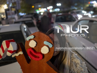 A young Iranian woman poses for a photograph while holding a Christmas accessory during Christmas shopping in downtown Tehran, Iran, on Dece...